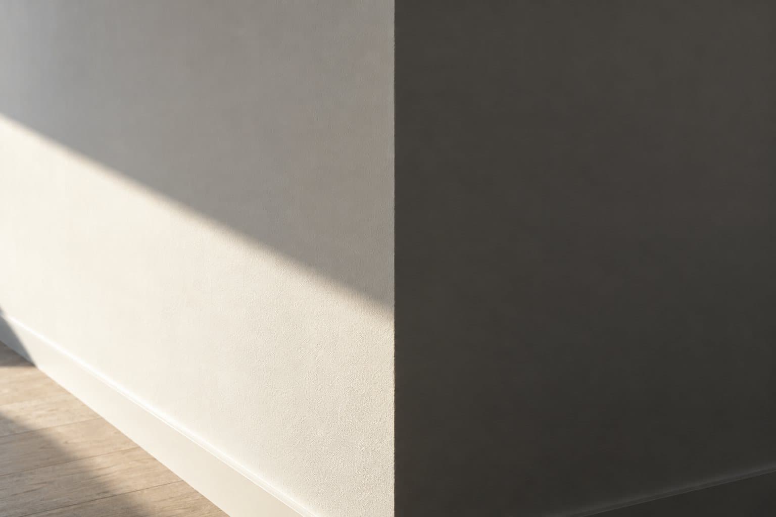 Angle vif d’un mur blanc mat balayé par une lumière rasante